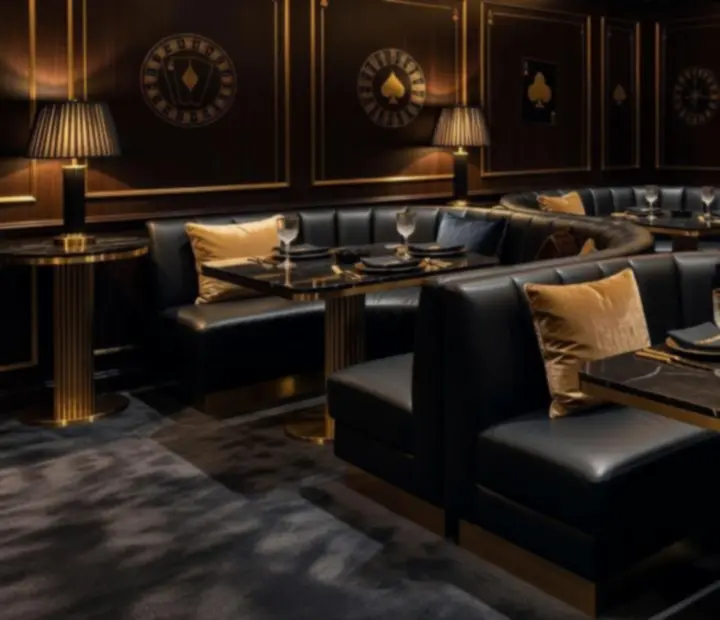 Luksuzni interijer lounge prostora s crnim i zlatnim tonovima, burgundy detaljima i ambijentalnim osvjetljenjem.